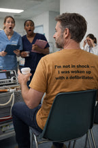 Man holding coffee wearing the I'm not in shock I was woken up with a defibrillator tee.