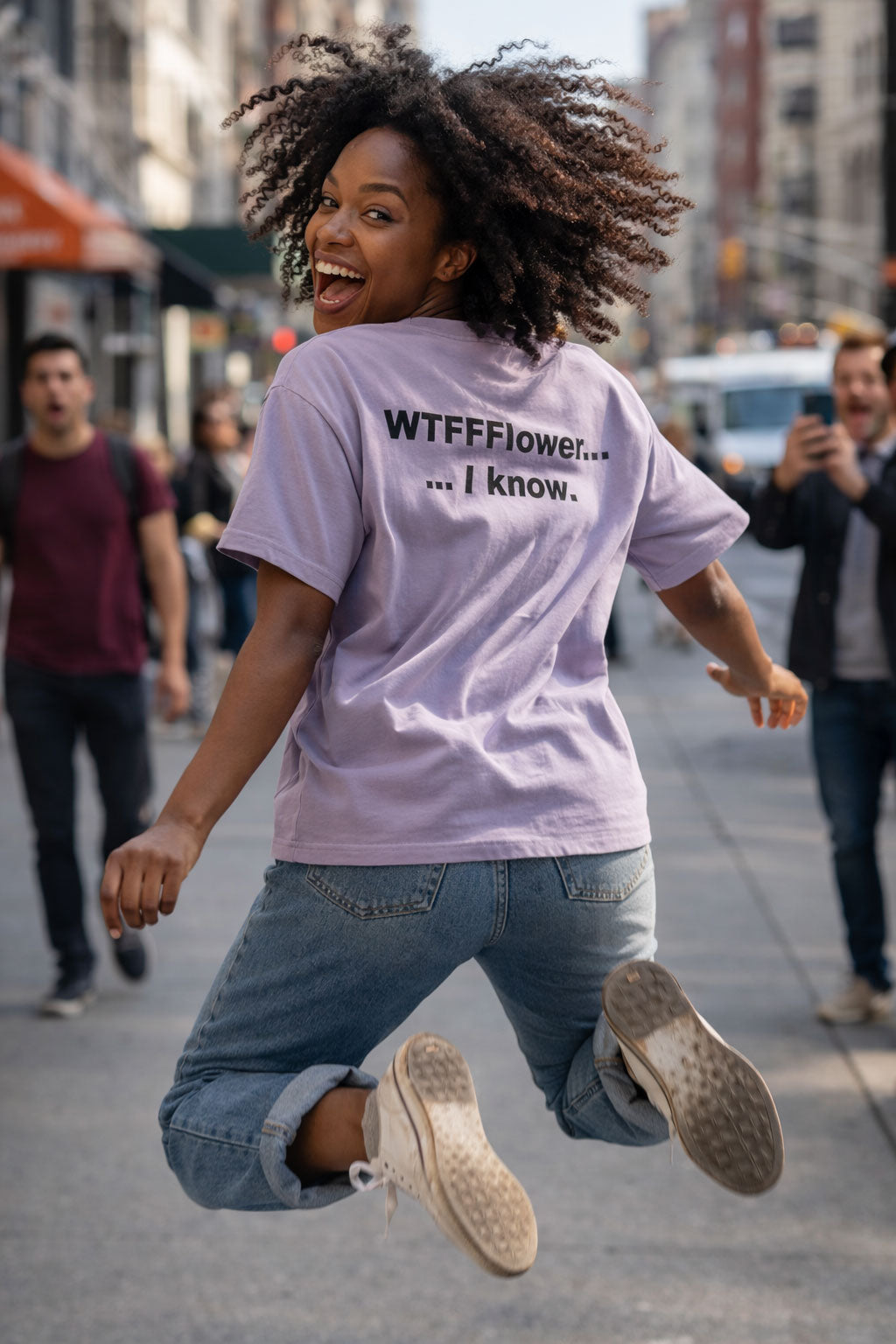 Energetic woman jumping on a city street in her WTFFFlower I know tee celebrating bold unique energy.