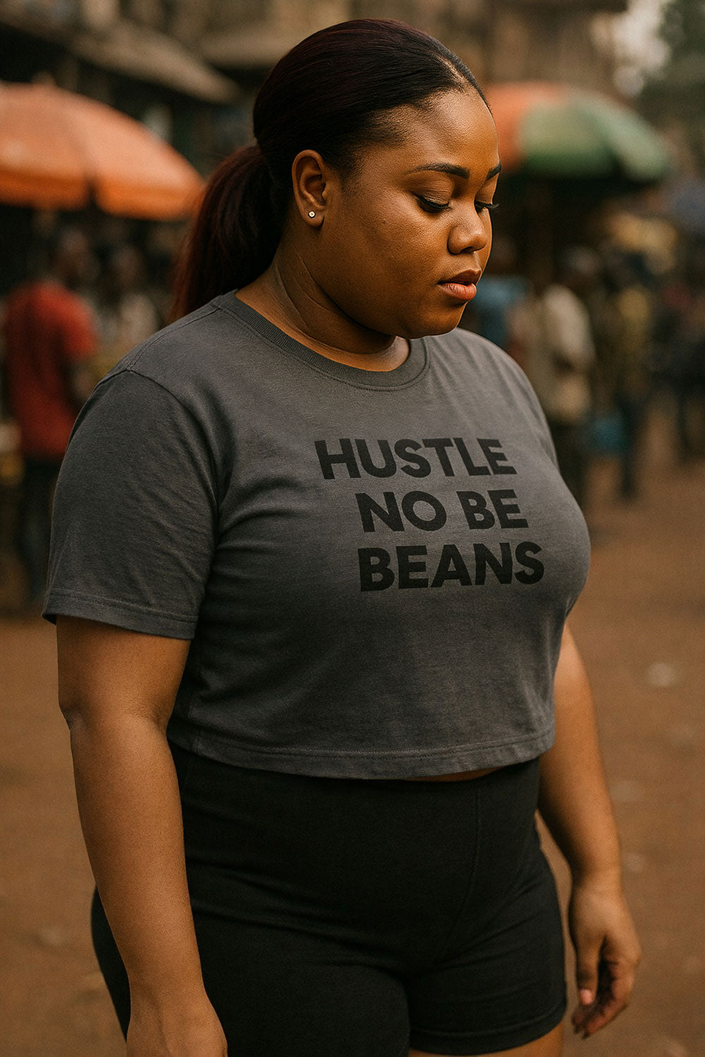 Serious woman look down wear hustle no be beans tee to respect her grind and keep moving.