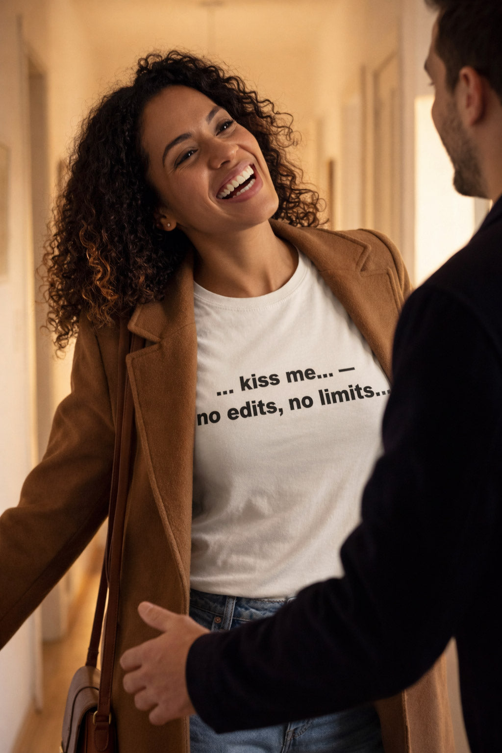 Smiling woman in hallway wearing the kiss me no edits no limits shirt showing raw affection perfectly.