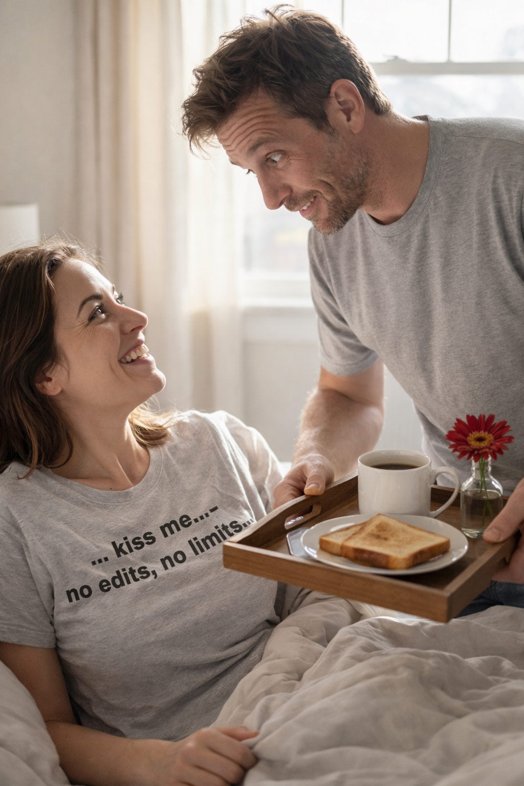 Happy woman in bed wearing the kiss me no edits no limits shirt sharing unguarded spontaneous moments.