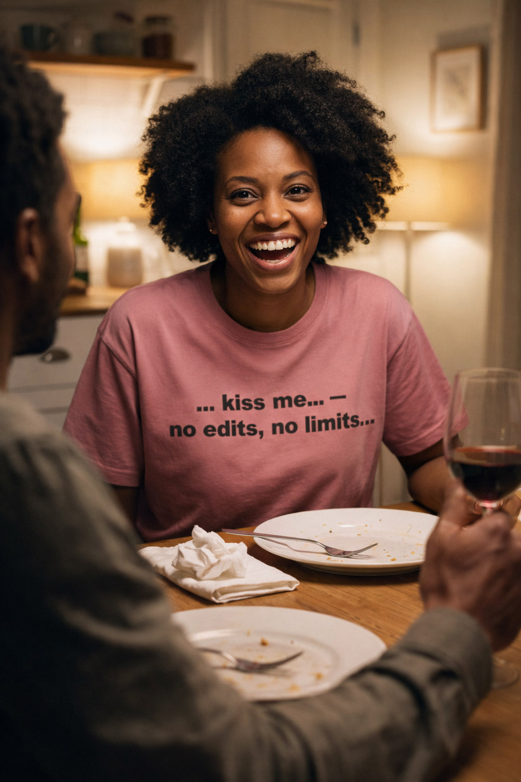 Laughing woman at dinner wearing the kiss me no edits no limits tee a meaningful partner gift.