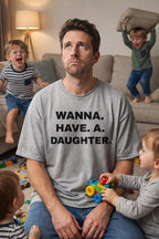 Overwhelmed man sitting with wild boys wearing wanna have a daughter shirt wishing for a gentle shift.