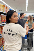 Playful woman shopping in an aisle wearing the hi ex miss me yet shirt a sarcastic present.
