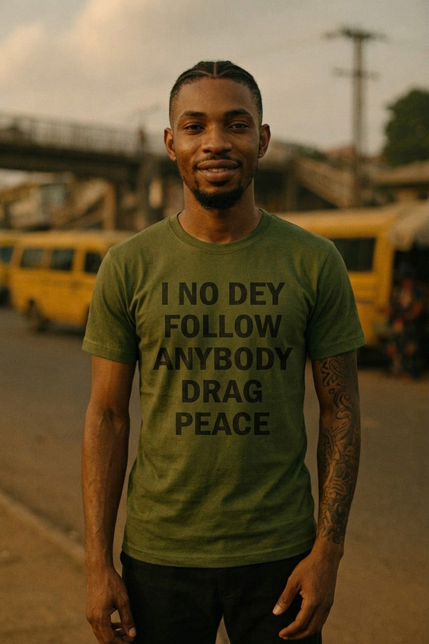Smiling young guy wear i no dey follow anybody drag peace tee to face his front without confusion.