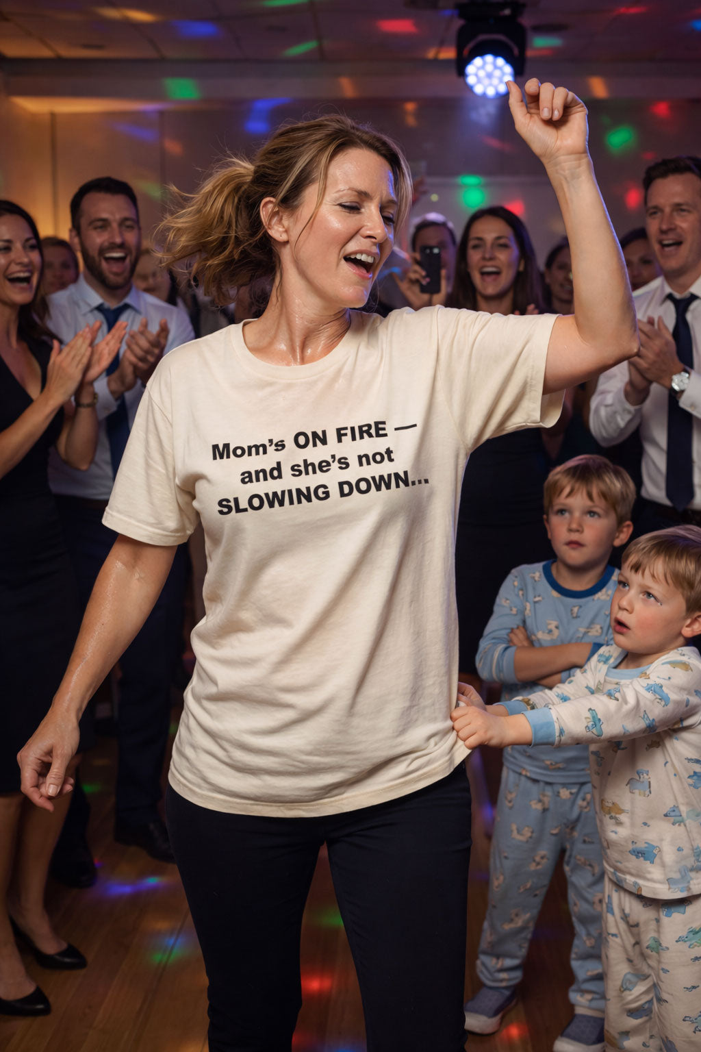 Energetic woman dancing at a party wearing mom's on fire and she's not slowing down shirt for mothers.