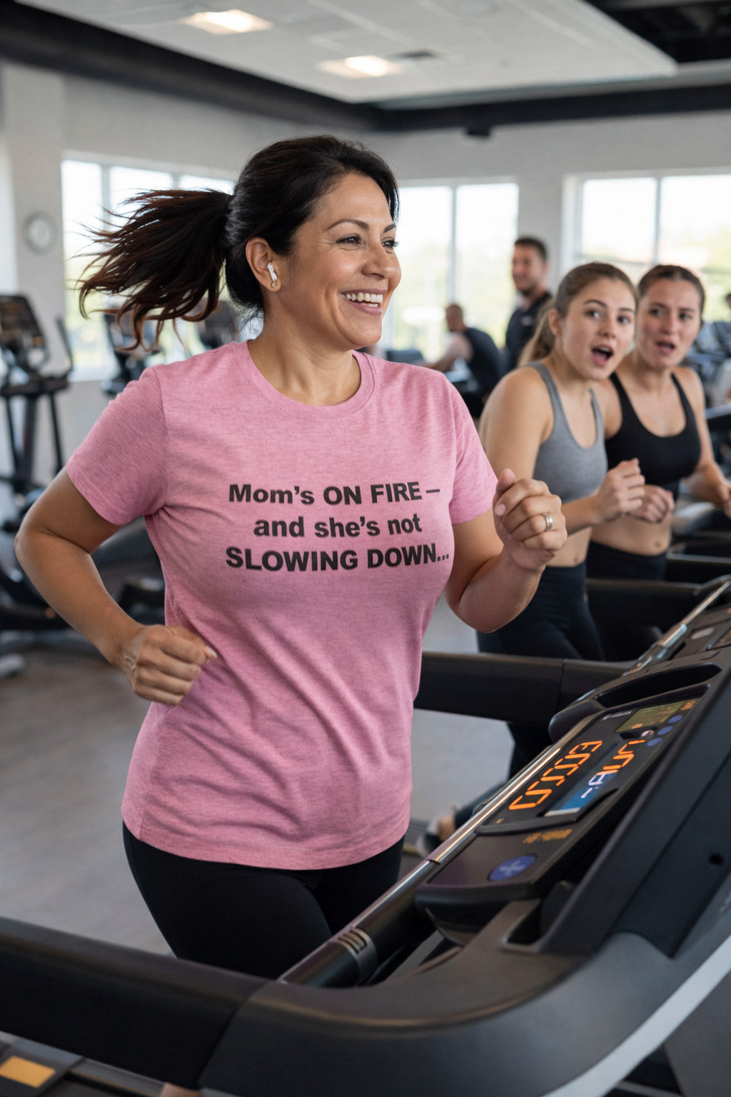 Smiling mother running on a treadmill in mom's on fire and she's not slowing down tee for athletes.