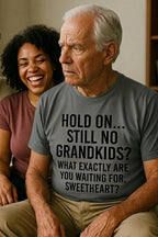 Older man sitting indoors wearing hold on still no grandkids disguising how deeply he cares, perfect gift.