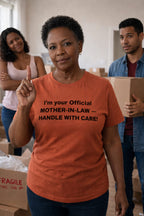 Proud woman standing by boxes wearing I'm your official mother-in-law handle with care shirt commanding respect.