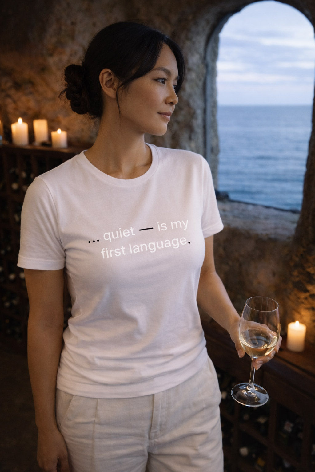 Elegant woman wearing quiet is my first language embracing reflection over reaction by a sea-view window.